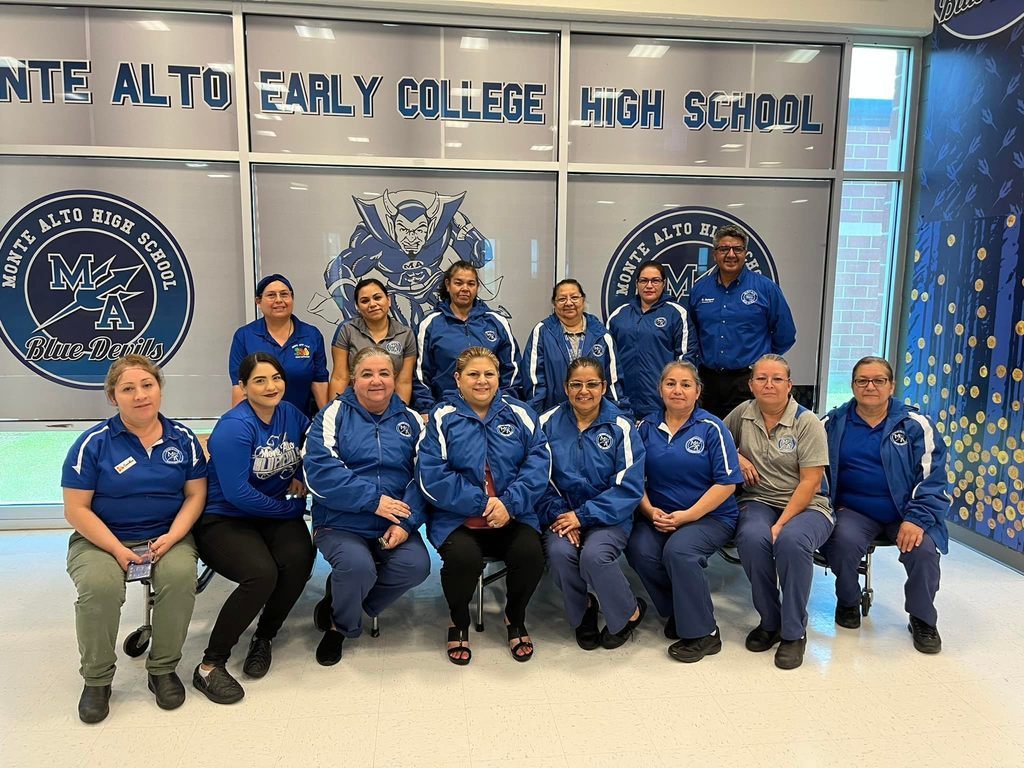 Cafeteria staff posed together in matching blue shirts